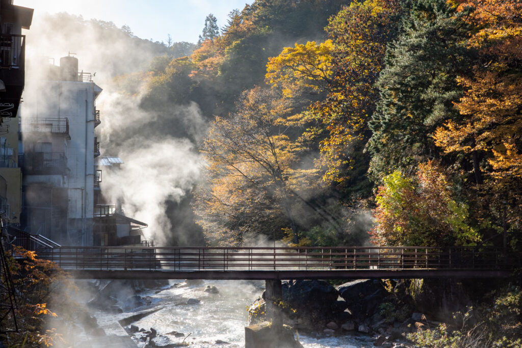 Hot spring steam rising beside the river in Shima Onsen, Japan