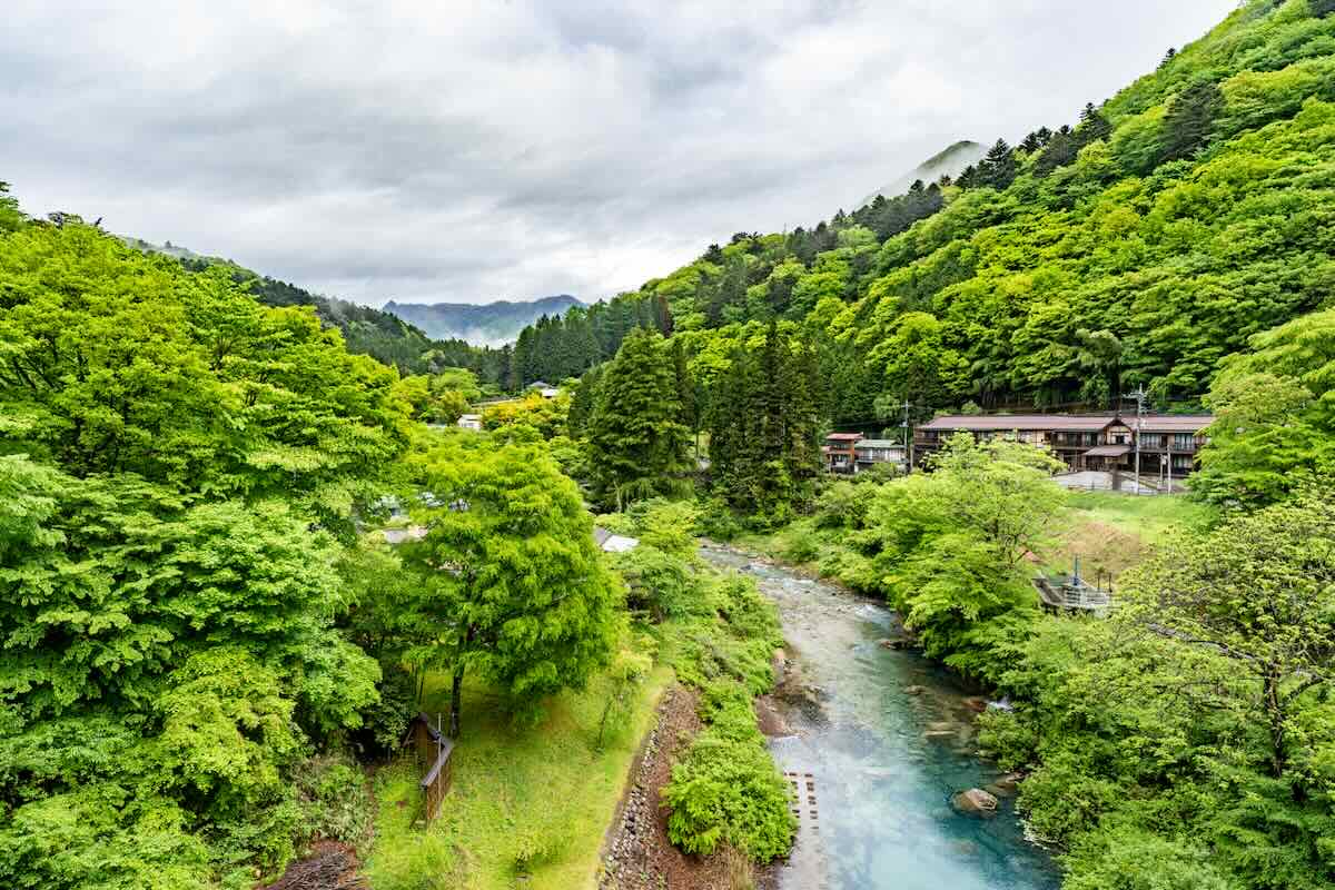 Shima River flowing through fresh green mountains in Shima Onsen, Gunma Prefecture
