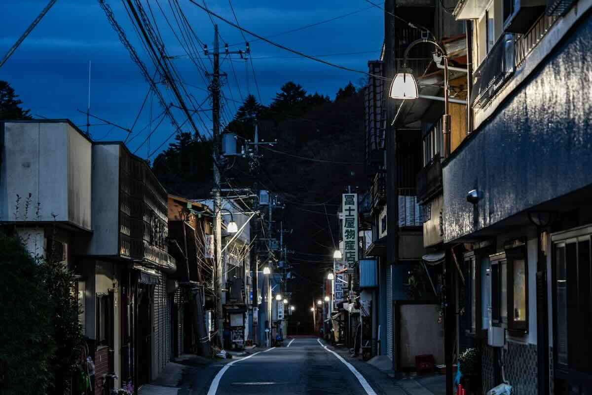 Quiet traditional street in Shima Onsen at dusk, with old shops and softly glowing streetlights